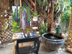 a canva painted on a tabe, it has brushes, colour and the tools to paint. Beside the table, there is a small fountain.