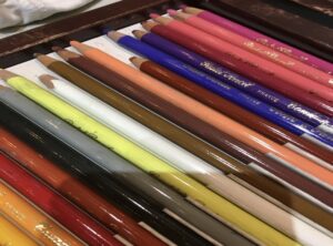 A close up look at colourful art pencil crayons lying flat on a surface, some of the tools Linda Lovisa uses to teach children in her art classes